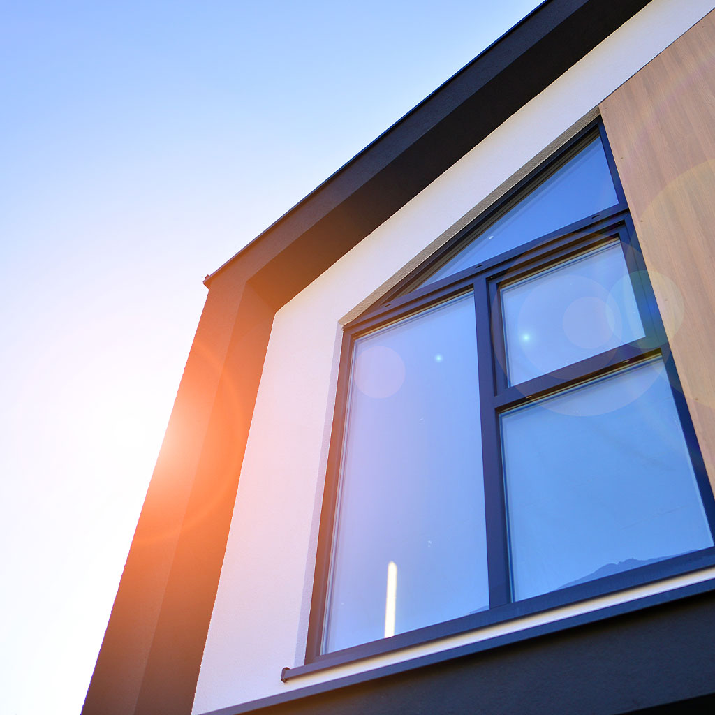 Neubau eines Einfamilienhauses mit Holzfassade und großen Fenstern im Gegenlicht